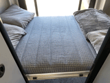 Cozy RV rental sleeping area featuring a patterned mattress, soft pillows, and blankets for comfortable travel.