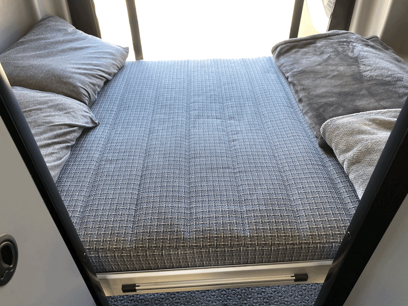 Cozy RV rental sleeping area featuring a patterned mattress, soft pillows, and blankets for comfortable travel. — photo 6