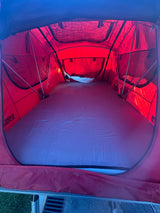 Inside a red rooftop tent, ideal for RV rental, featuring a comfortable mattress for your next outdoor adventure.