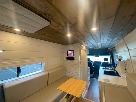 Modern RV rental interior: spacious living, dining, and kitchen area for comfortable travel adventures.