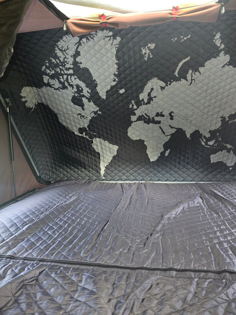 Cozy RV rental interior: a quilted world map adorns the ceiling above a matching, comfortable bed.