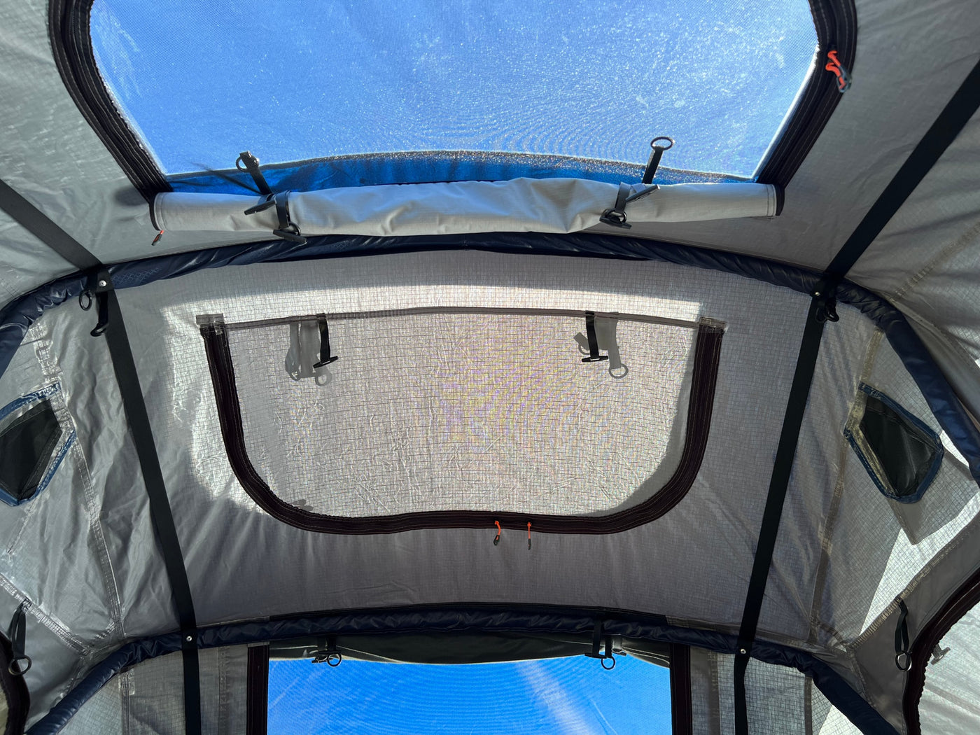 Inside an RV rental's rooftop tent: view of the blue sky through an open skylight and zippered mesh window. Perfect for camping. — photo 15