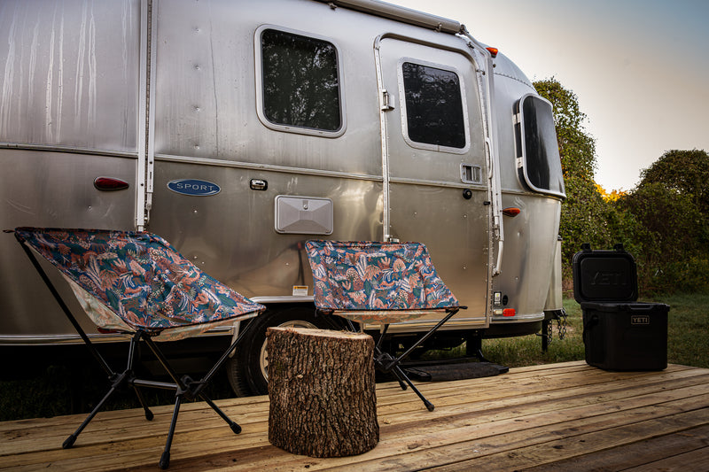 An Airstream RV rental on a wooden deck with two vibrant chairs, a tree stump, and a YETI cooler. Perfect for outdoor glamping. — photo 5