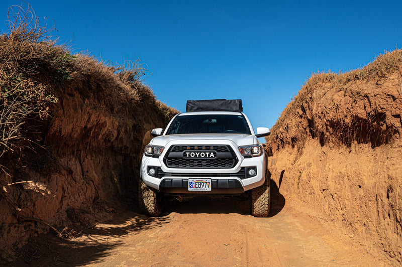 A white Toyota Tacoma navigates a narrow, dry dirt path. This robust truck is an ideal vehicle for a thrilling RV rental adventure. — photo 7