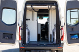RV rental camper van's organized rear interior with open doors revealing storage pockets and a clear path leading to the front cabin.