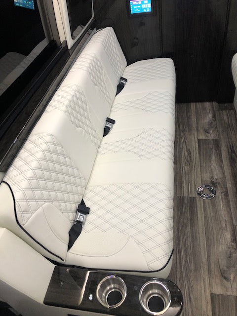 Experience comfort in this RV rental's custom luxury interior: white quilted seating, integrated cupholders, & control screen. — photo 7