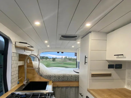 Spacious RV rental interior with a cozy bed, full kitchen, and scenic view, perfect for mobile living adventures.