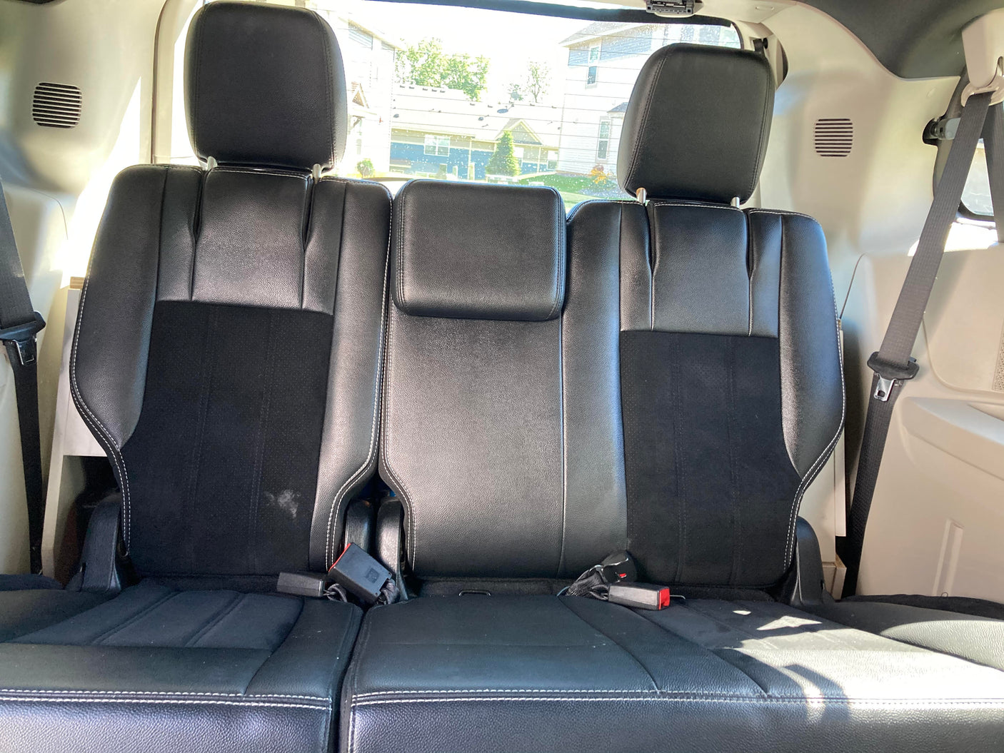 RV rental: Interior view of black third-row seating with white stitching and visible seatbelts.