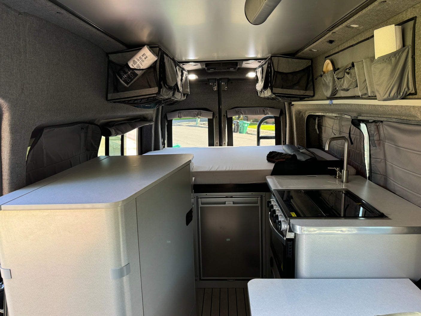 Modern RV rental camper van interior. Features a compact kitchen, comfortable bed, fridge, and ample storage for your trip.