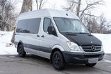 Silver Mercedes Sprinter van, an RV rental with a black hood, parked in snowy terrain. Your adventure camper awaits!