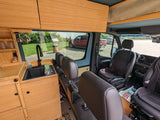 Custom-built RV rental interior with bamboo kitchen, sink, and comfy seats for your next adventure.
