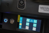 Inside an RV rental, a touchscreen control panel manages power, lights, internet, water pump, and tank heaters, with physical buttons for master power and refrigerator.