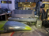 Adventure-ready RV rental interior: a kayak on the floor, custom elevated bed, rear bench seat, and gear storage.