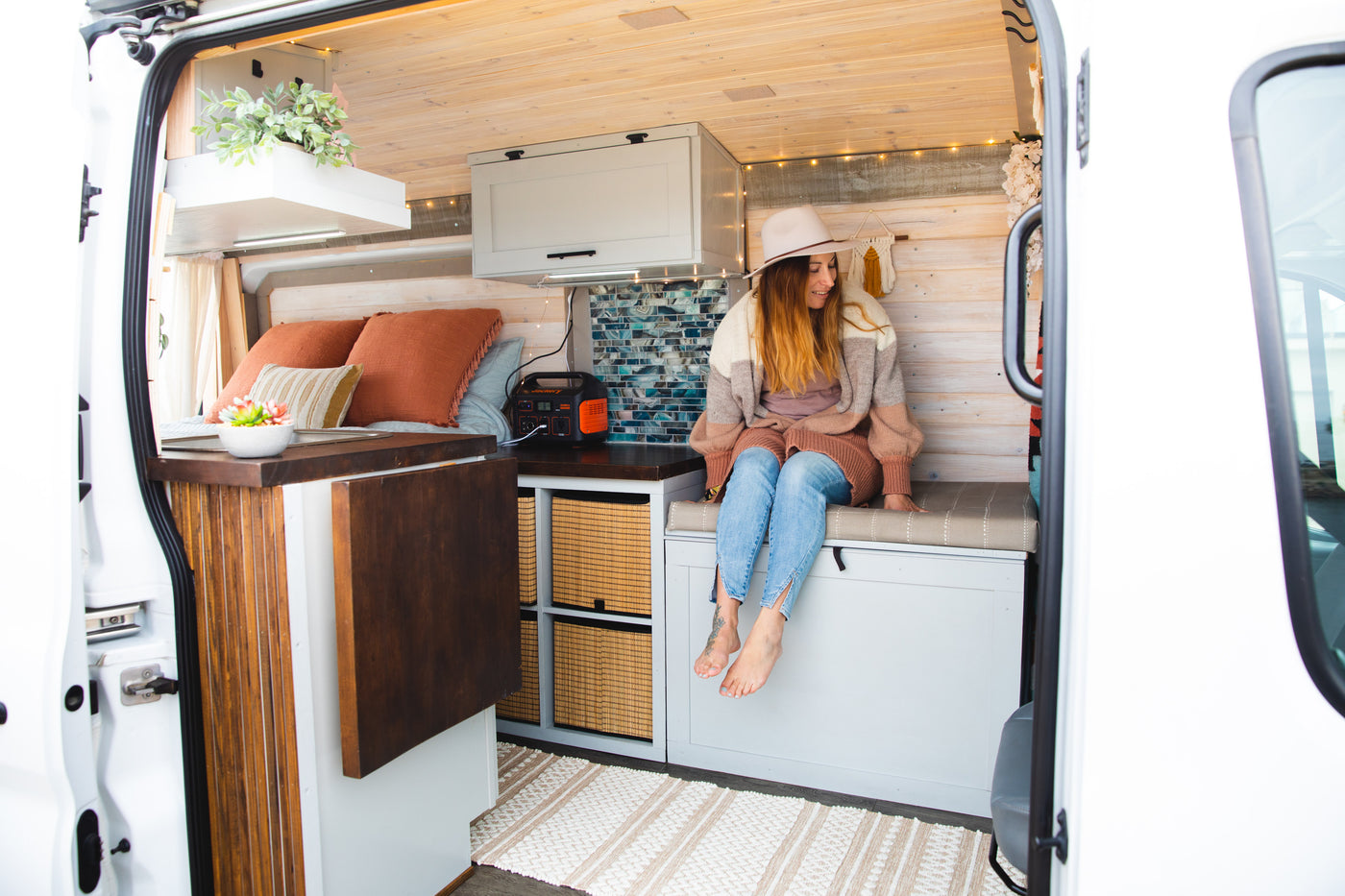 Step inside this charming RV rental! A woman relaxes in the beautifully designed camper van interior. — photo 2
