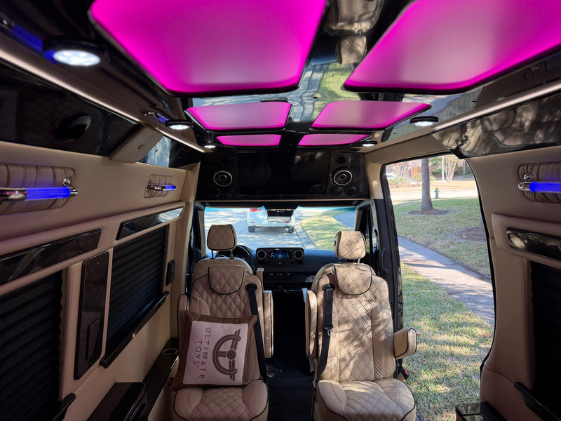 Luxury rv rental interior with plush, quilted tan seats, vibrant pink ceiling lights, and blue accent lighting, offering premium comfort. — photo 9