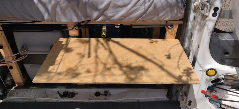 RV rental: Inside a camper van, a bed base is seen with a water tank and plumbing underneath for a compact setup. — photo 11