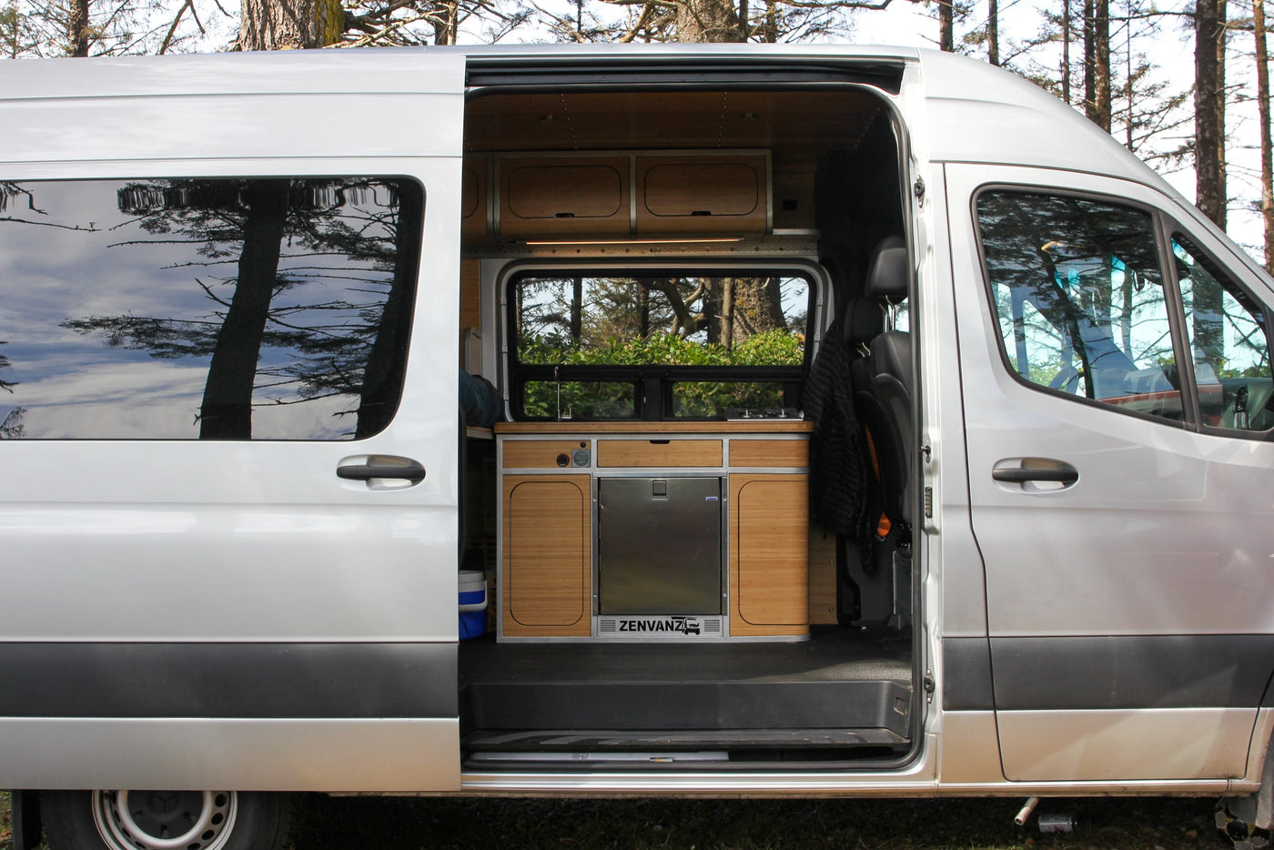 Silver RV rental: open door reveals custom Zenvanz camper interior with kitchenette, fridge, and cabinets. Ready for adventure! — photo 2