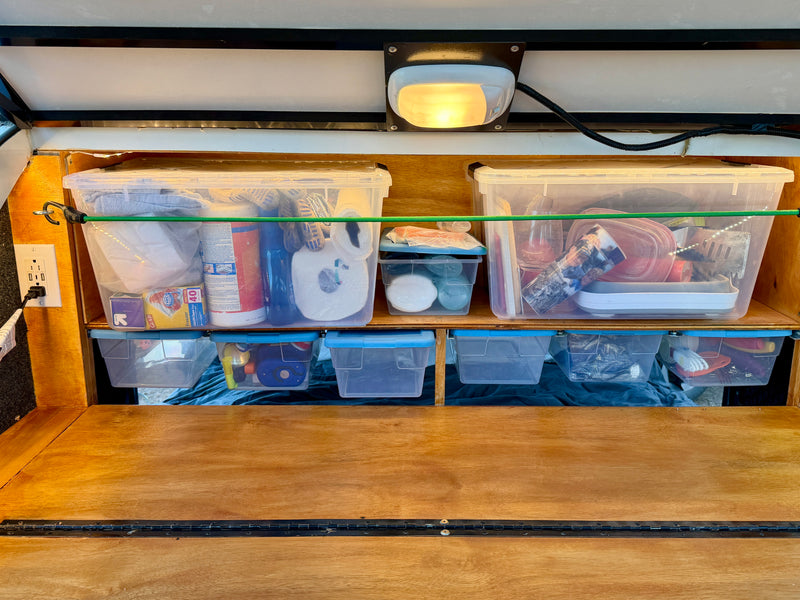 Efficient RV rental storage with clear bins, bungee cords, and an outlet, keeping essentials organized. — photo 11