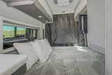 Inside a modern RV rental: a plush bed, scenic window view, and TV offer comfort on the road.