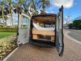 Experience van life with this rv rental! Grey camper van with open back doors revealing a wood-paneled interior, bed, and storage.