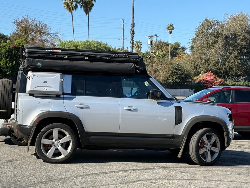 A silver Land Rover Defender with a Roofnest rooftop tent and side gear box, perfect for an adventure RV rental. — photo 12