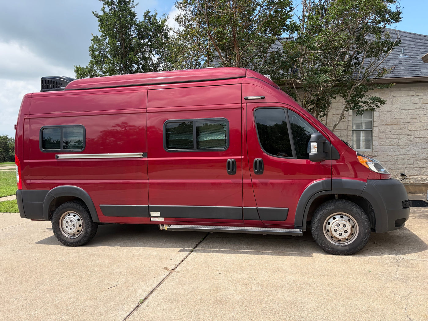 Red camper van parked on concrete, featuring a rooftop AC and side step. Ideal for your next RV rental adventure! — photo 6