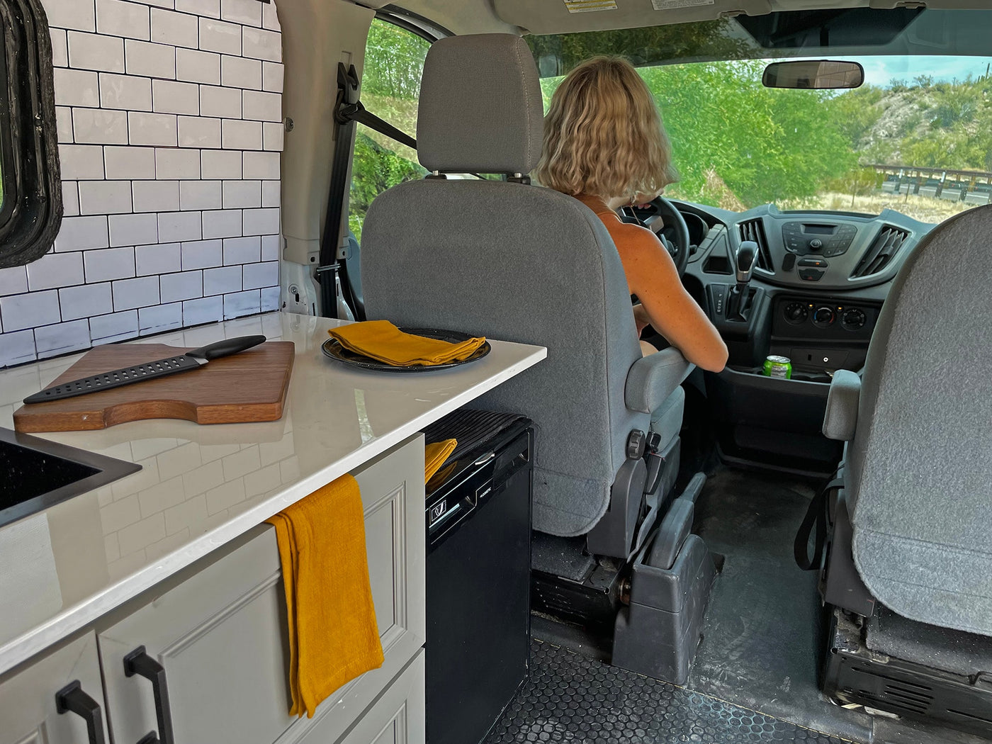 Inside this rv rental, a driver navigates a custom van with a compact kitchen, perfect for mobile living and travel. — photo 16