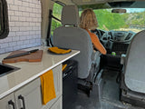 Inside this rv rental, a driver navigates a custom van with a compact kitchen, perfect for mobile living and travel.