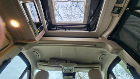 Experience an RV rental: a bright interior with a large skylight, built-in microwave, and essential control panel.