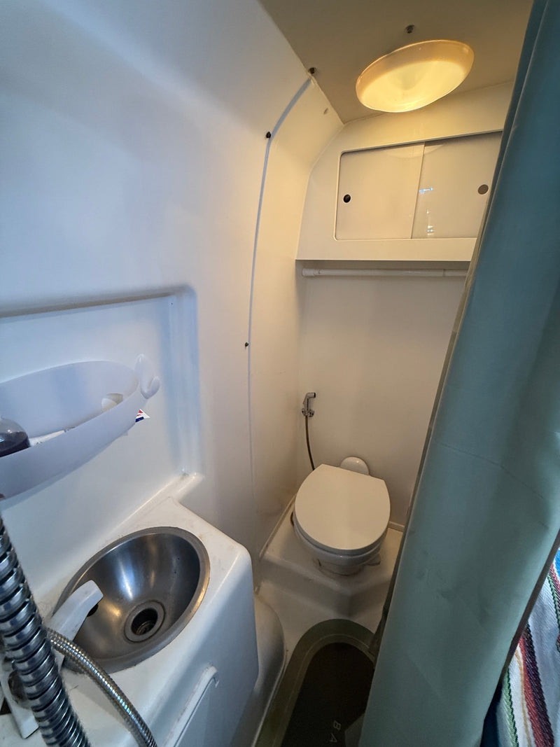 This RV rental's compact bathroom features a sink, toilet with bidet, and shower area for efficient use of space. — photo 12