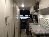 Inside an RV rental: view of the compact kitchen with sink, microwave, and extensive cabinetry for storage.