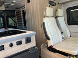 Inside a functional RV rental: discover the compact kitchen, comfortable quilted seating, and wall-mounted solar controls.