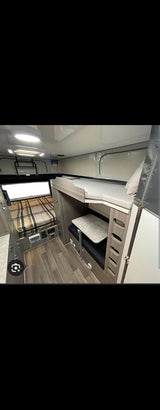 Inside a modern rv rental, showing a main sleeping area, integrated bunk beds, and a dining table, ideal for compact travel.