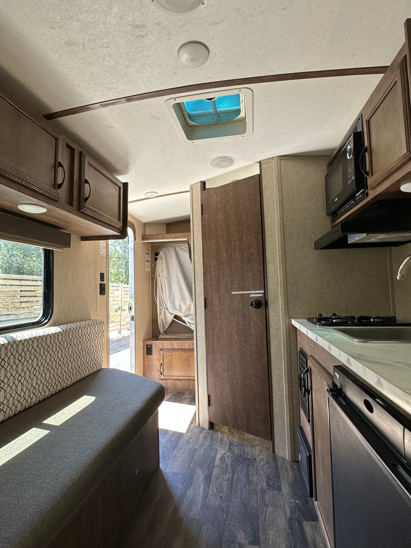Inside this RV rental: a practical kitchen with stove and sink, a cozy dinette, and wood-look flooring. Ready for travel! — photo 5