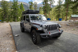 Gray Jeep Wrangler Rubicon with rooftop tent, ideal for your next RV rental adventure amidst mountains.