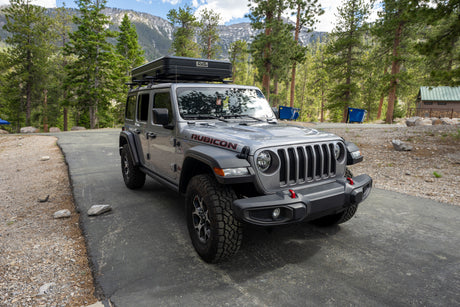 Gray Jeep Wrangler Rubicon with rooftop tent, ideal for your next RV rental adventure amidst mountains.
