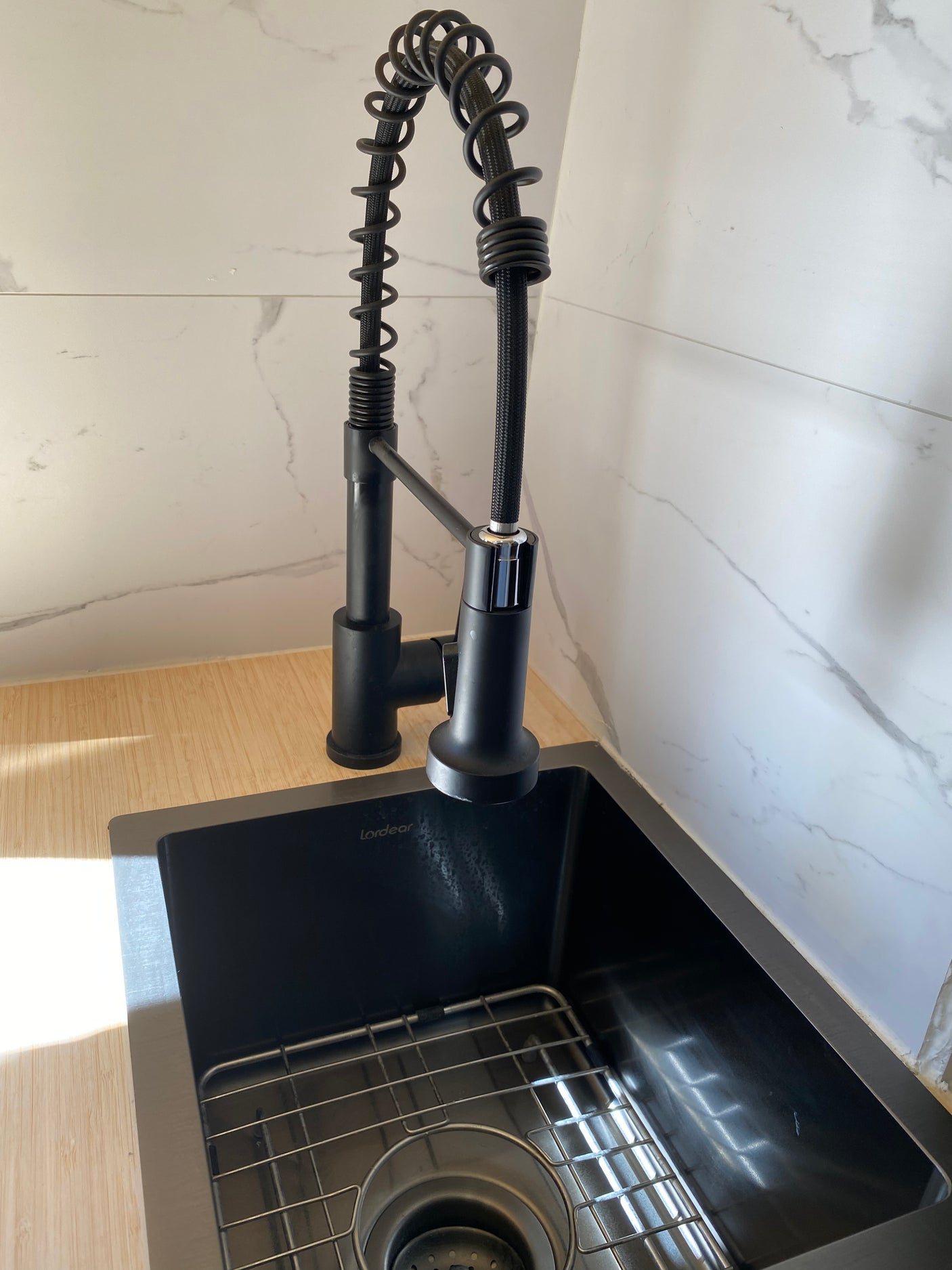 Modern black kitchen sink and pull-down faucet with wood counters and marble backsplash, perfect for your RV rental.