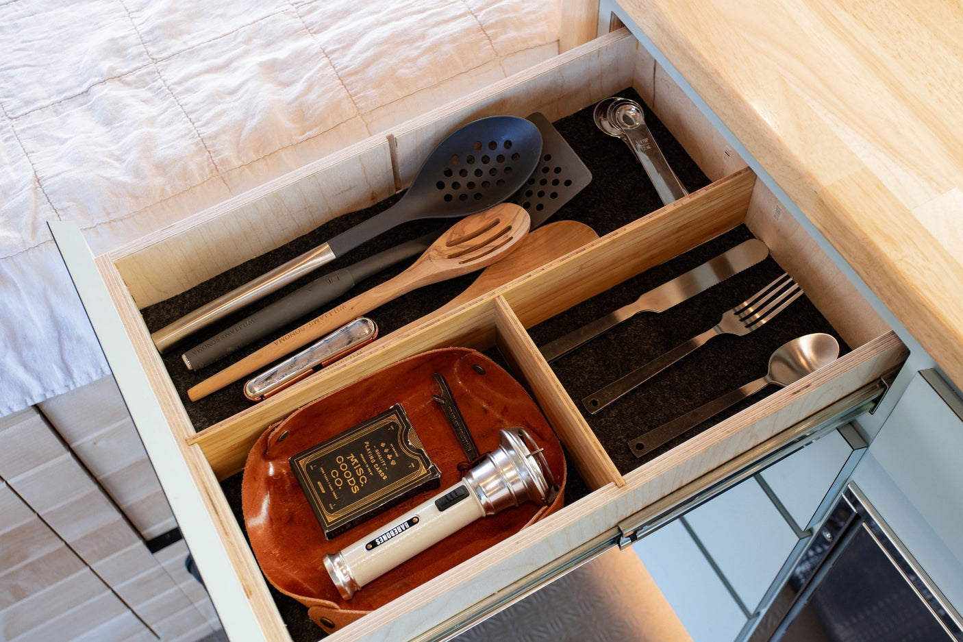 Inside an RV rental, discover an organized drawer: kitchen utensils, flatware, cards, and a flashlight. Compact storage!