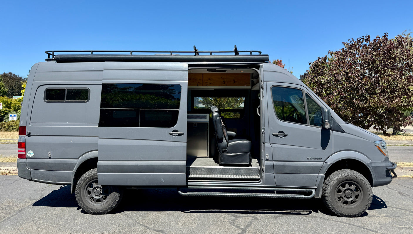 Spacious grey custom camper van with open side door revealing its interior, perfect for your next rv rental adventure.
