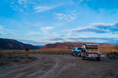RV rental truck with an open camper kitchen set up in a vast desert landscape at sunset/sunrise. Remote camping adventure awaits!