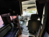 Spacious RV rental interior: view from rear lounge towards cockpit of a converted Sprinter van with TV & seating.