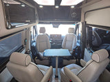 Luxury RV rental interior with comfortable captain's chairs, dining table, and overhead entertainment.