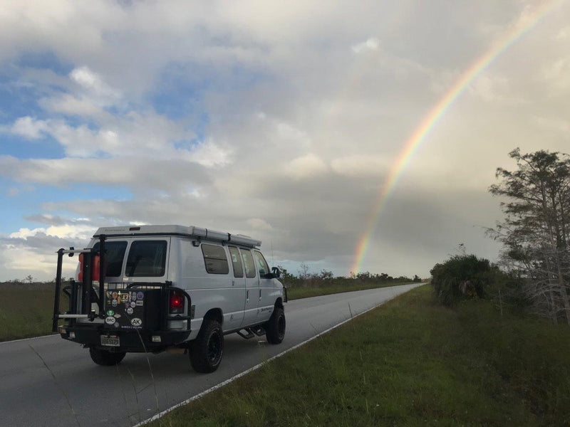  with a bright rainbow arching over a marshy landscape.|Explore in a white 4x4 pop-top camper van — photo 2