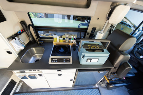 RV rental kitchenette: compact sink, induction cooktop, portable fridge, and storage. Perfect for on-the-go camper van cooking.