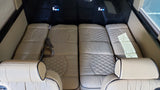 Spacious luxury RV rental interior with four plush, quilted beige seats that convert to beds, offering comfort for travel.