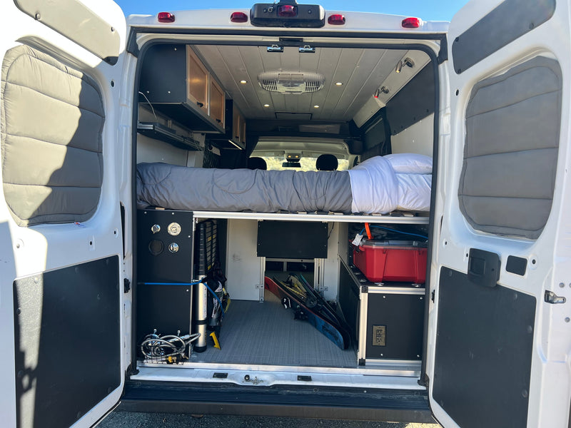 Inside this RV rental camper van: a cozy raised bed, ample storage, and skis, perfect for your next adventure. — photo 15