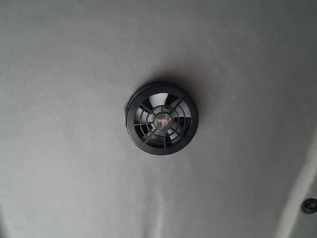 Essential for your rv rental: a ceiling-mounted ventilation fan. Features a black vent cover on a light gray fabric headliner.