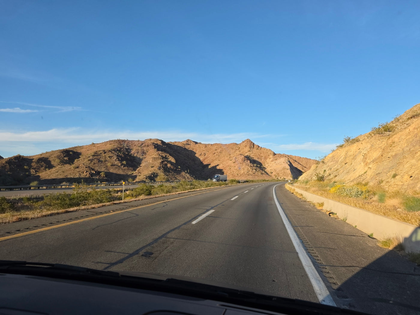Scenic desert mountains and a winding highway on a sunny day, ideal for an RV rental road trip. A truck is visible ahead. — photo 19