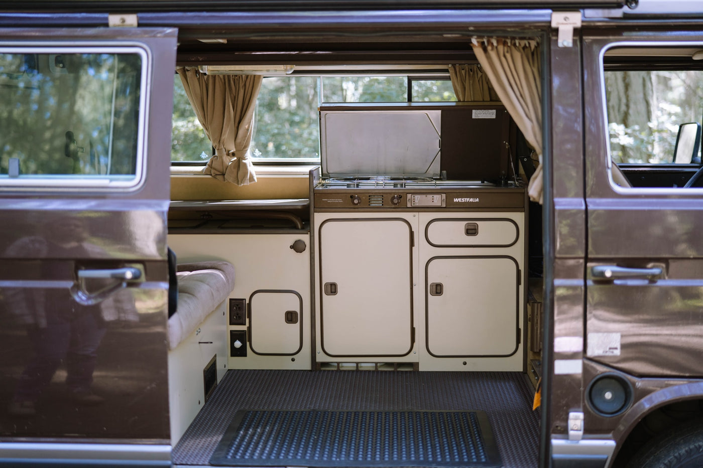  parked in a sunny forest with its pop-top extended.|A brown camper van named 'Hazel' (WA plate) with its rear hatch open — photo 5