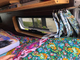Relaxing RV rental interior: colorful quilted bed, window, and books on a shelf for cozy travels.